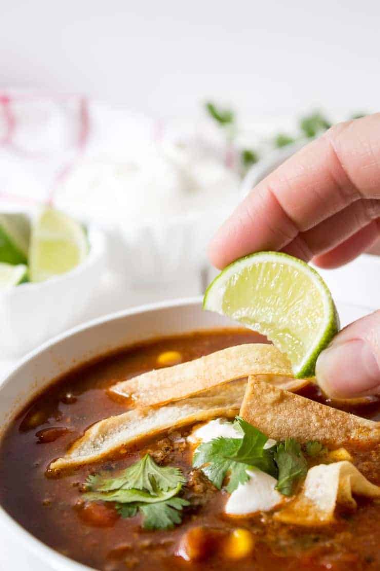 A fresh squeeze of lime on a delicious bowl of enchilada soup.