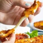 Crispy fried mozzarella stick being pulled apart.