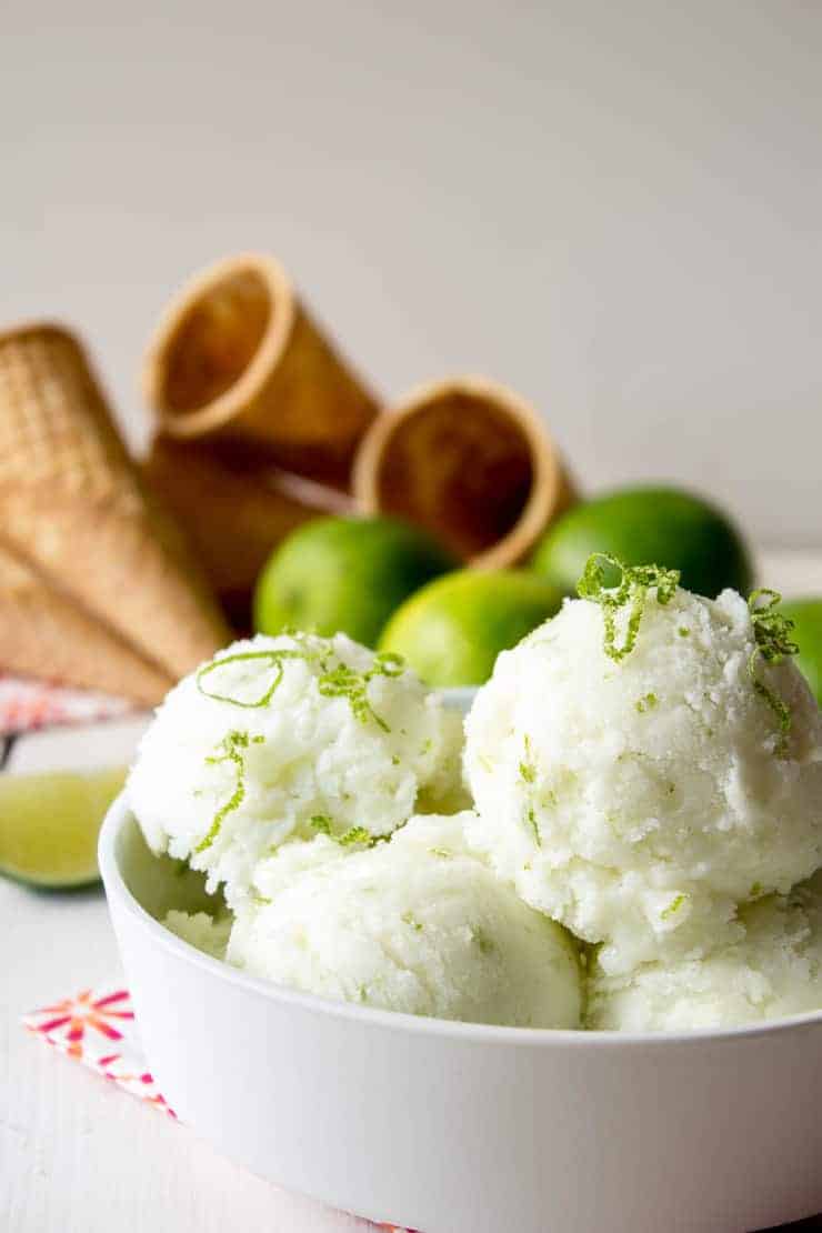 A white bowl filled with scoops of sherbet topped with fresh lime zest.
