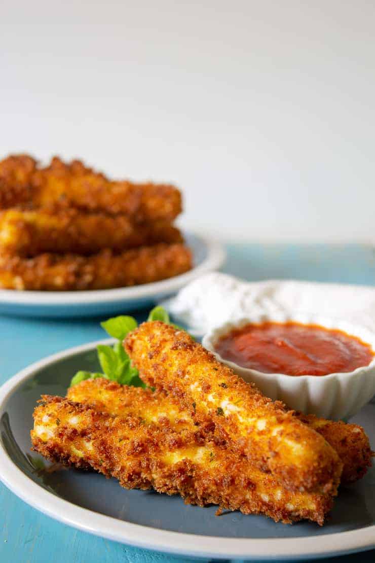 A blue plate with three cheese sticks on the plate.