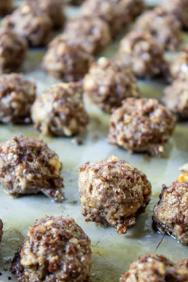 Cooked cocktail meatballs cooling on baking sheet.