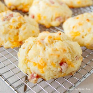 Biscuits with ham and cheese on a baking rack.
