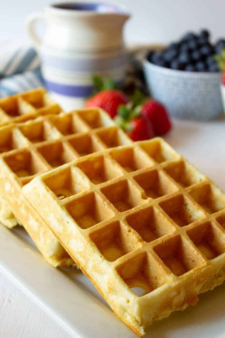 A stack of three waffles on a white platter.