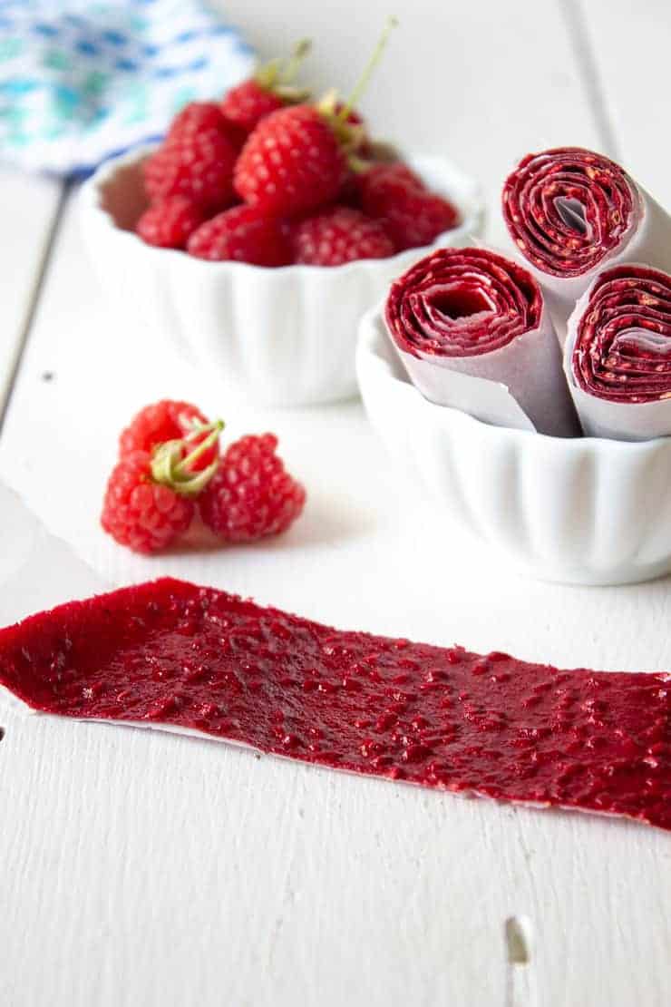 Raspberry fruit leather roll out on a white board.