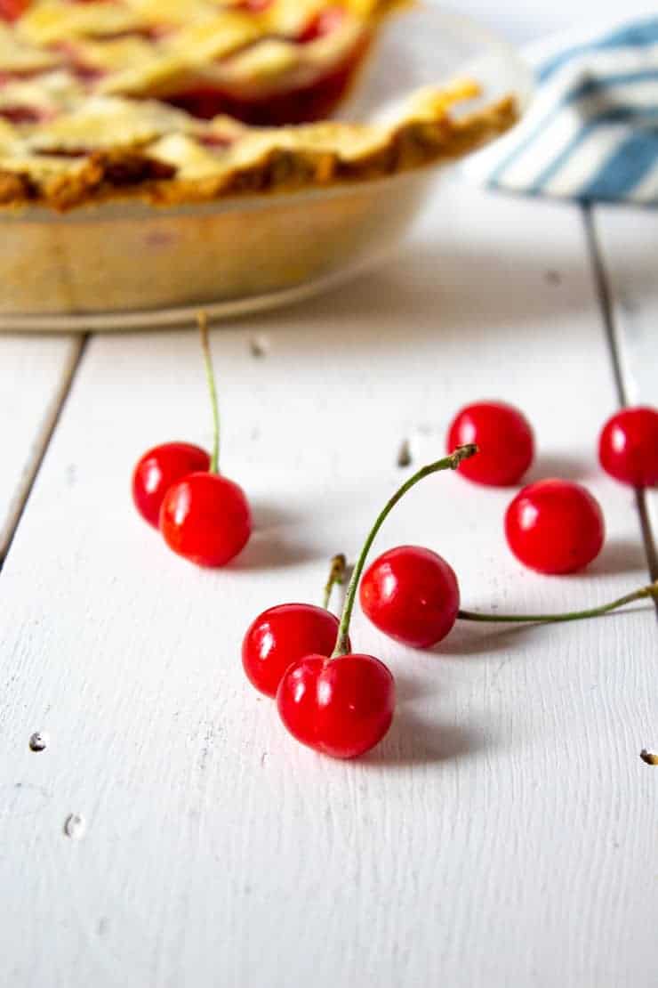 Freshly picked pie cherries next to a homemade cherry dessert.