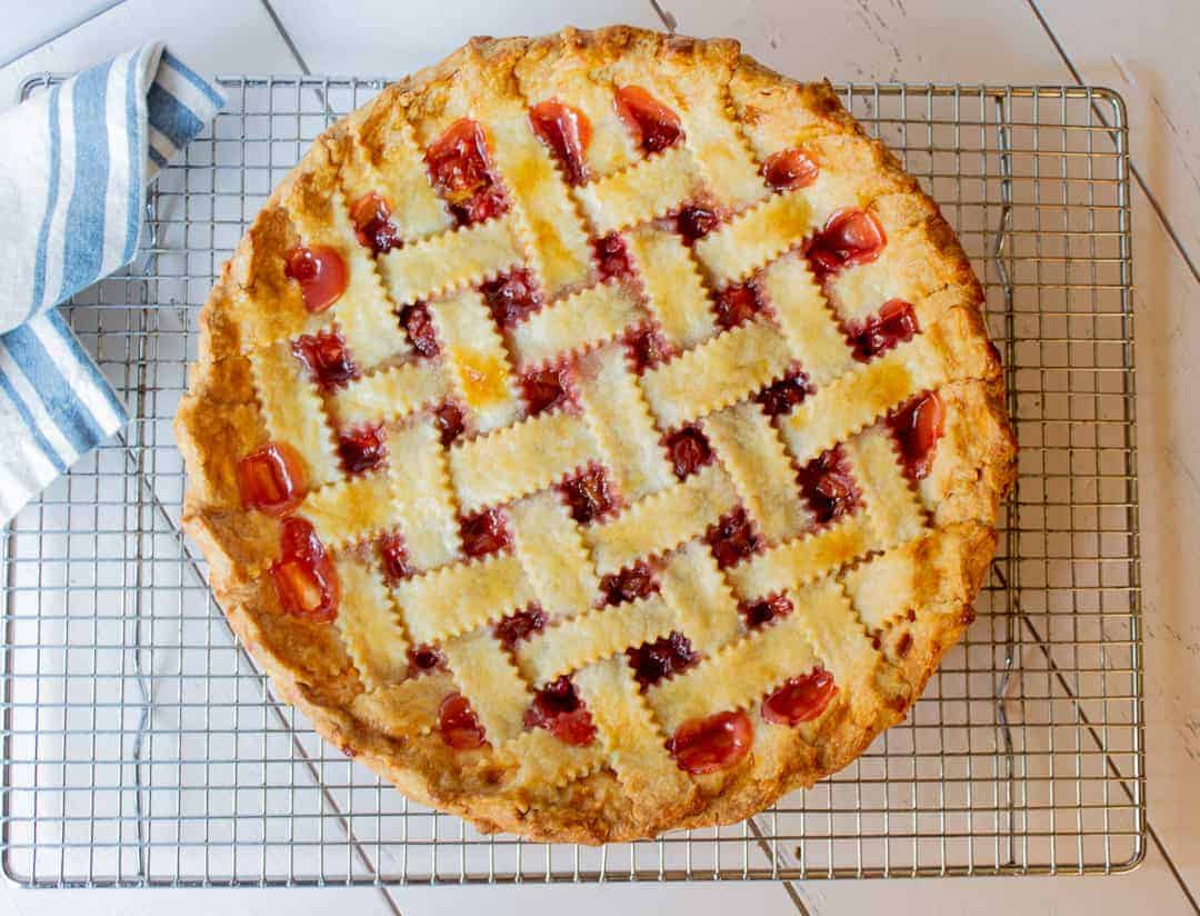 Homemade Cherry Pie with a lattice crust on a baking rack.