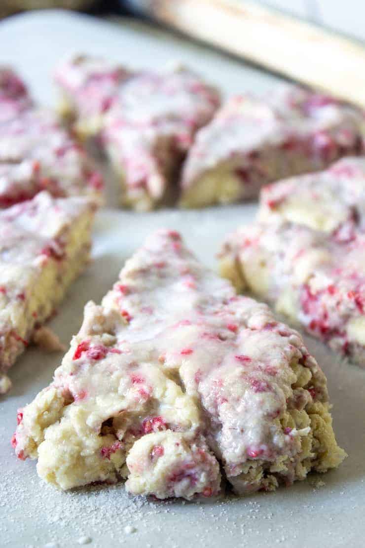 Raspberry scone dough on a baking sheet covered with cream.
