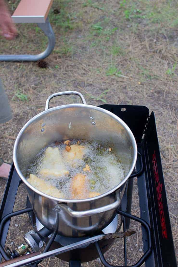Beer battered fish being cooked in camp