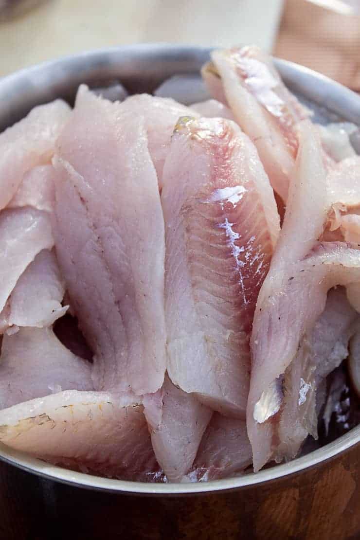 A large pot filled with fillets of walleye fish.