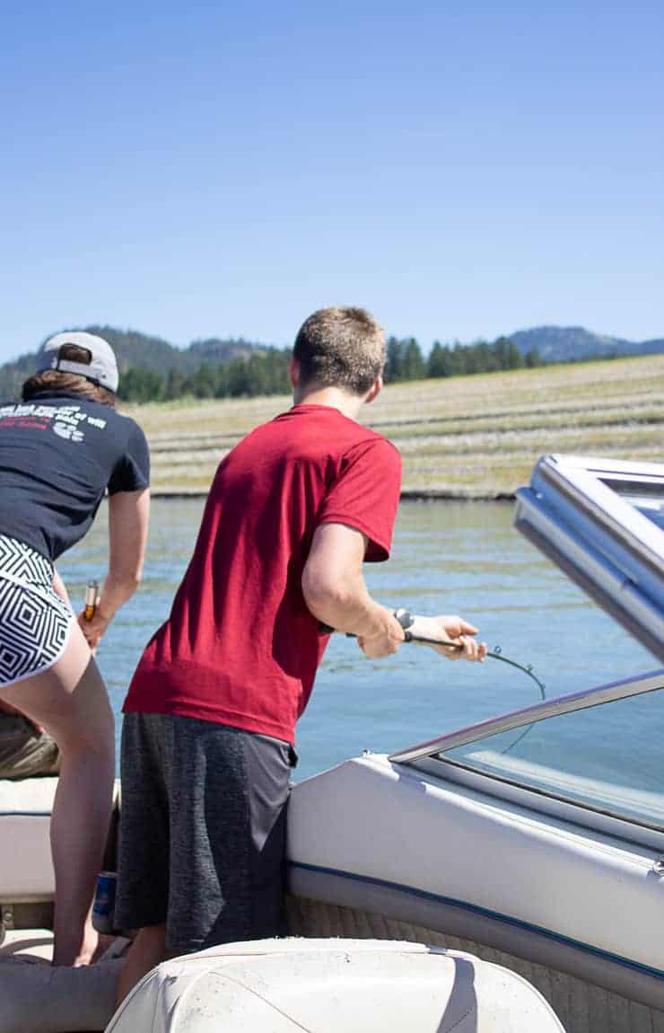 Two people fishing from a boat on a river.