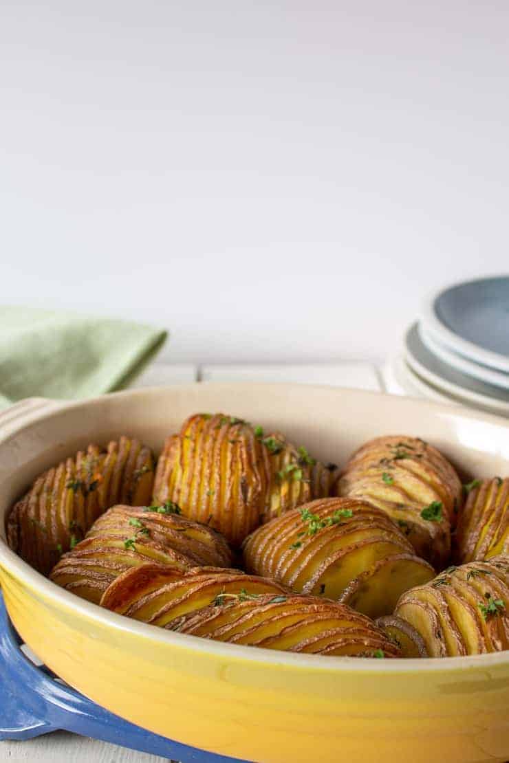 A yellow casserole dish filled with roasted hasselback potatoes.