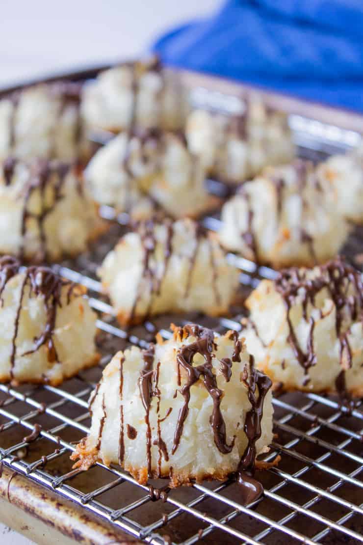 Coconut Macaroons drizzled with milk chocolate on a baking rack.