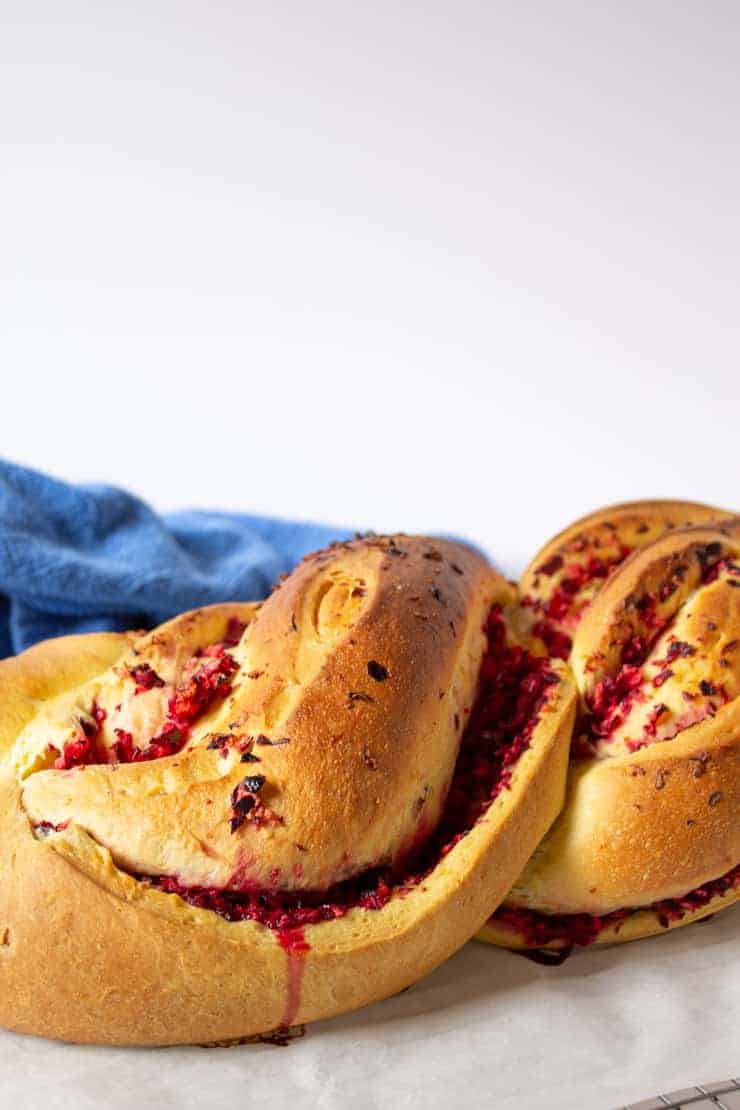 A loaf of cranberry twisted bread on a piece of parchment paper.