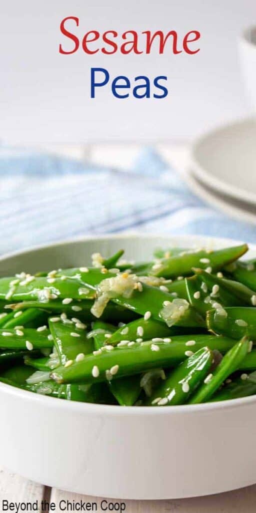 A white bowl filled with fresh pea pods topped with sesame seeds.