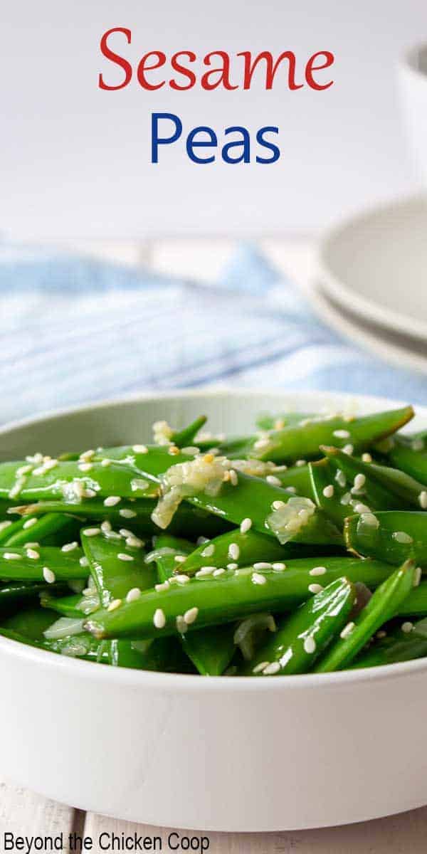 A white bowl filled with fresh pea pods topped with sesame seeds.