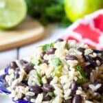 A colorful bowl filled with black beans, rice and herbs.