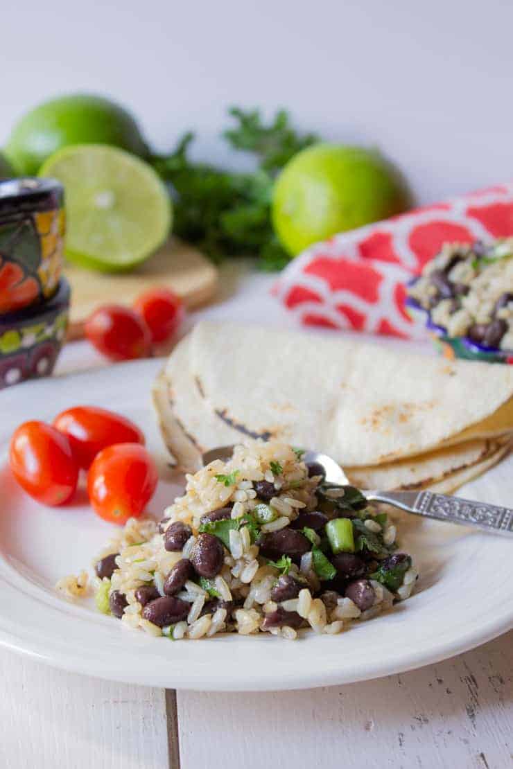 A plate filled with rice and beans mixed together along with tortillas. 