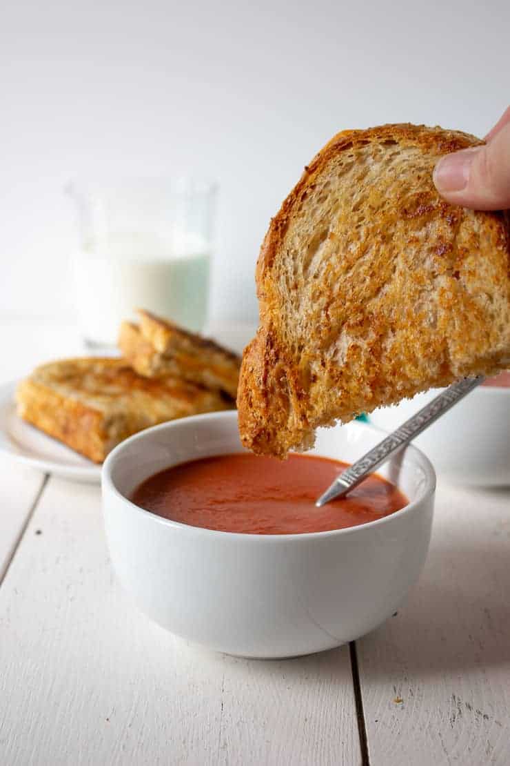 A crispy grilled cheese sandwich and a bowl of creamy tomato soup.