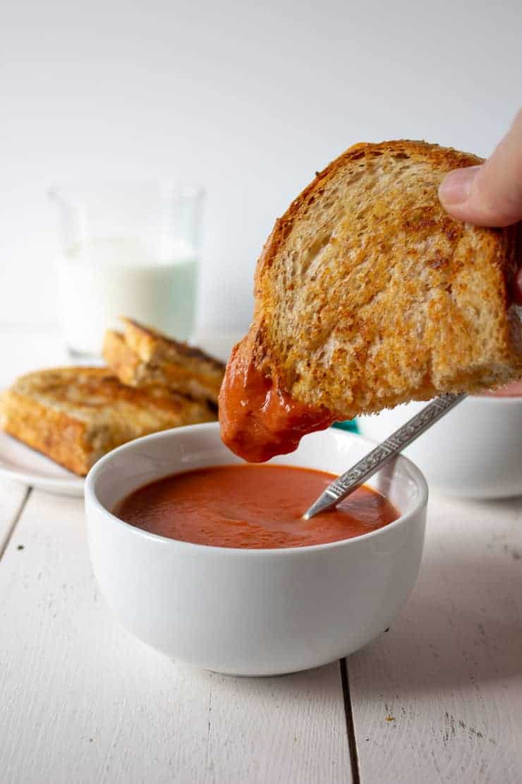 A grilled cheese sandwich dipped into creamy tomato soup.