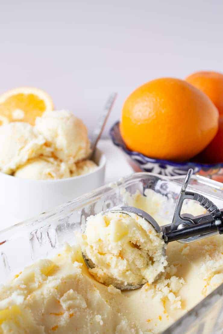 Homemade Orange Sherbet being scooped up with an ice cream scoop.