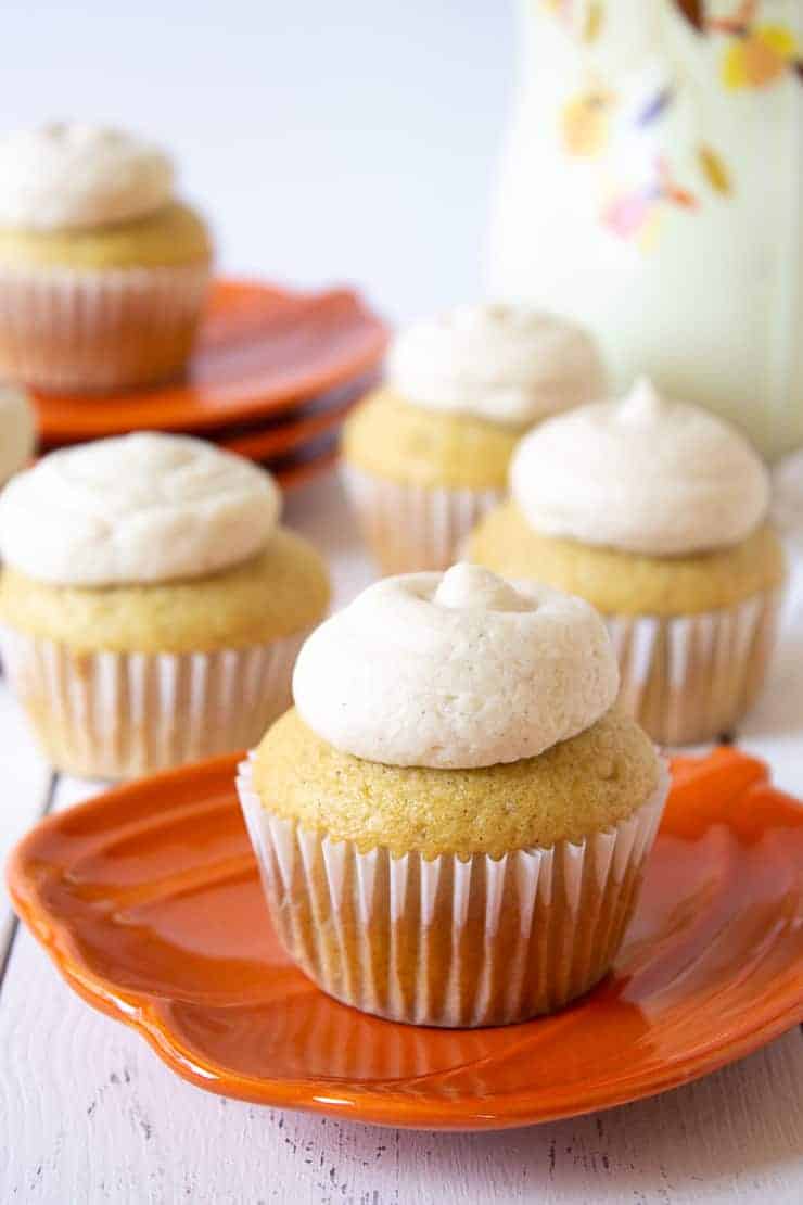 Cupcakes topped with a dollop of frosting on an orange plate.