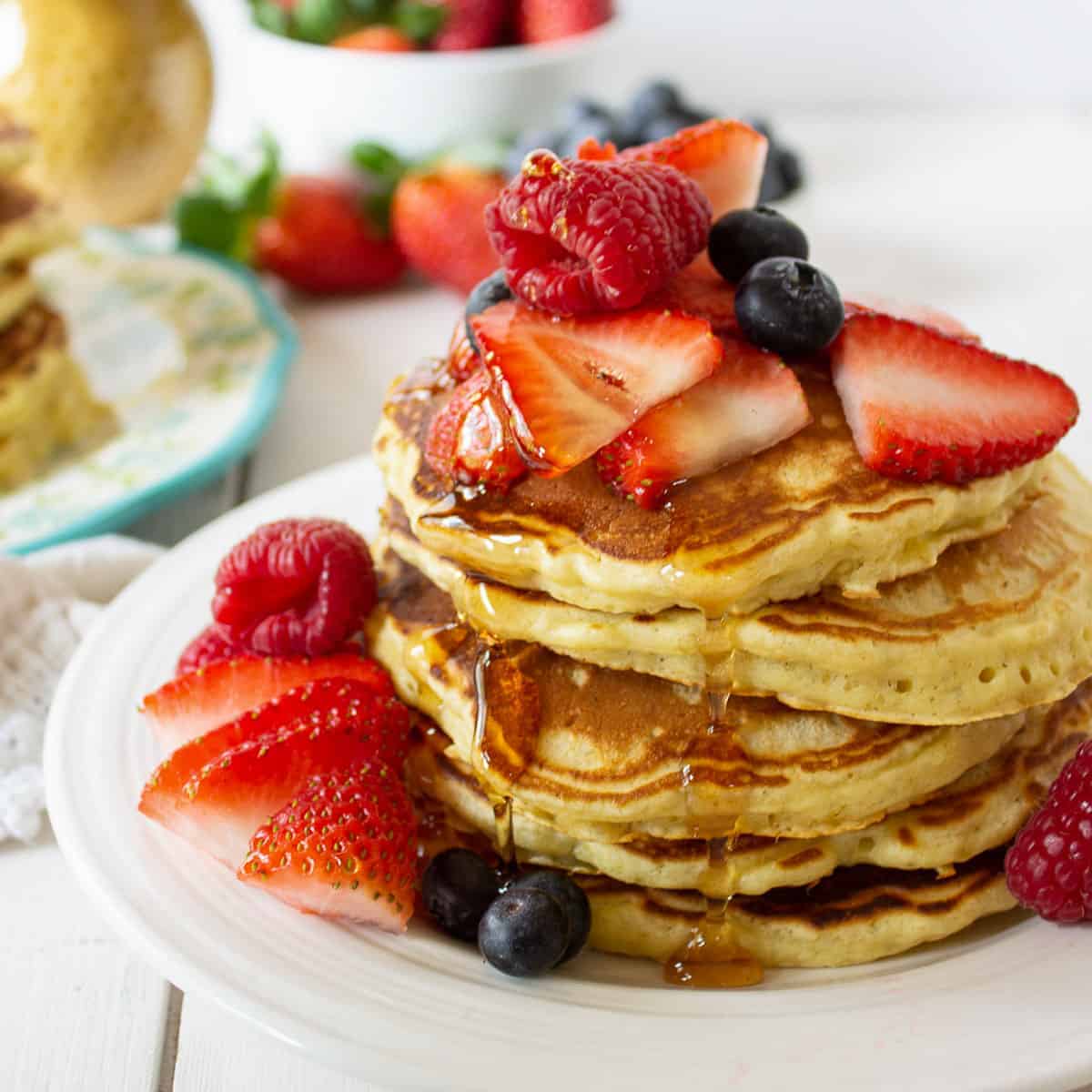 A stack of pancakes topped with fresh fruit and syrup.