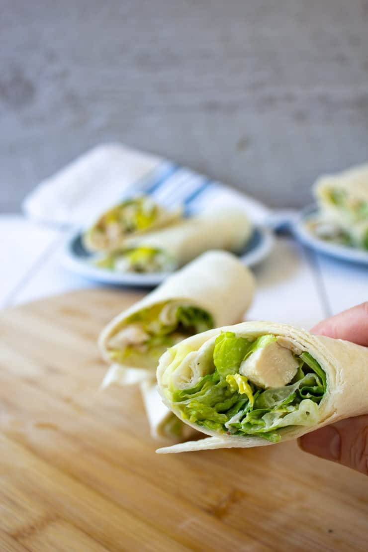 Chicken Caesar Wraps being held with one hand.