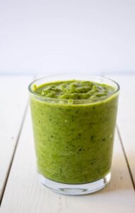 Green Smoothie in a glass on a white board.