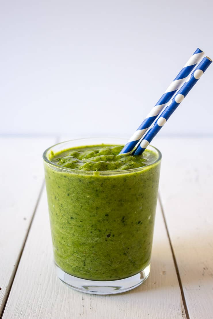A green smoothie with a blue and white straw