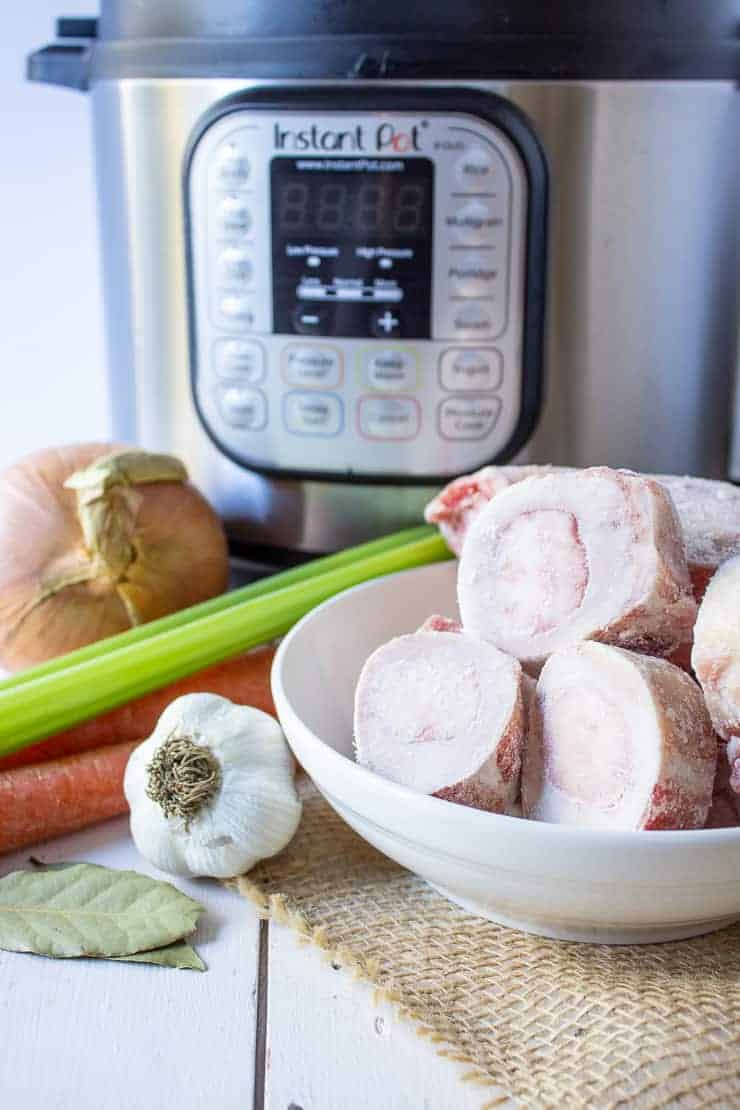 Ingredients needed for instant pot bone broth. Includes bones, garlic, carrots, celery and onion.
