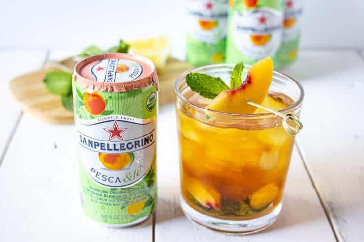 Sparkling Lemon Peach Tea Mocktail with a can of Sanpellegrino next to it.