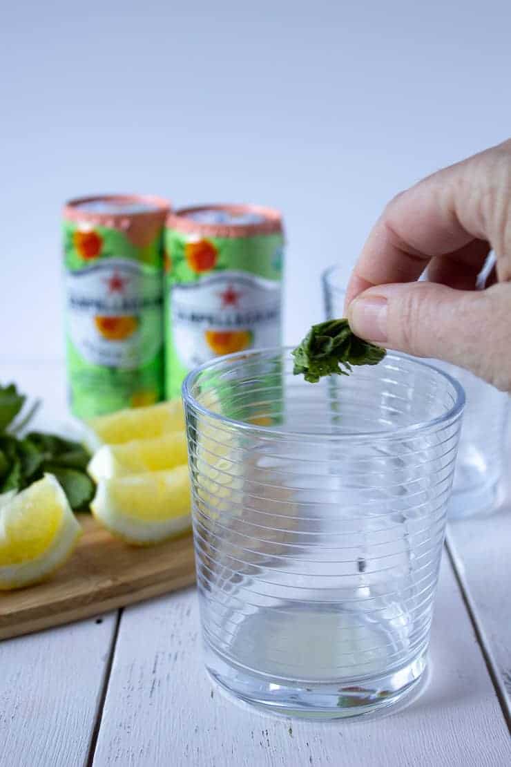 Adding smashed mint leaf into a glass.