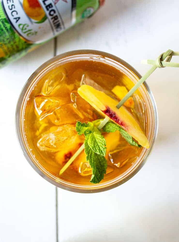 Sparkling Lemon Peach Tea with a fresh mint leave and a slice of peach for a garnish.