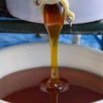Honey pouring from a large spout in a large white bucket.