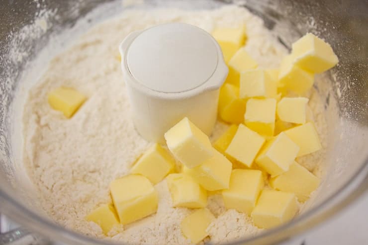 A food processor with a flour mixture and small cubes of butter.