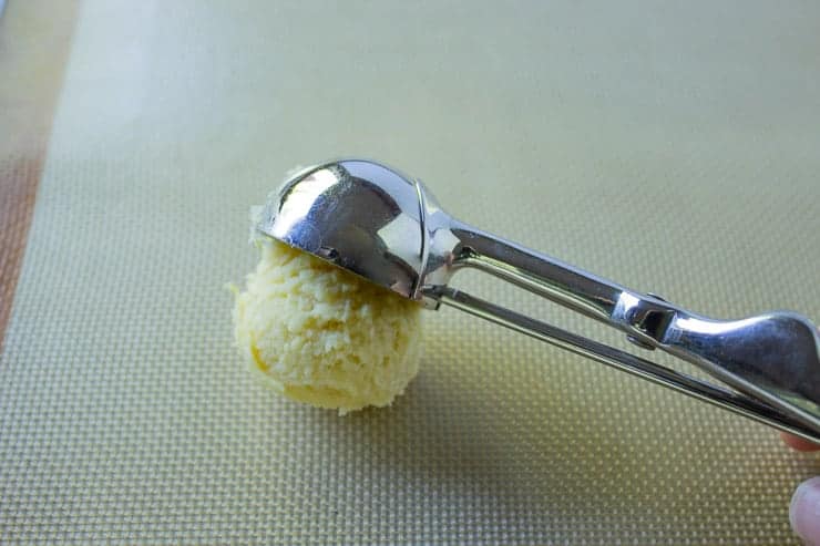 A scoopful of lemon sugar cookie dough on a baking sheet.