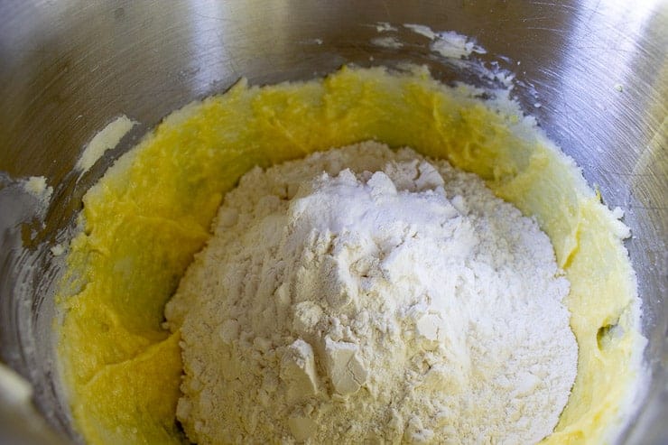 Cookie dough in a mixing bowl with flour mixture being added. 