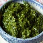 Basil pesto in a small white bowl with a blue rim.