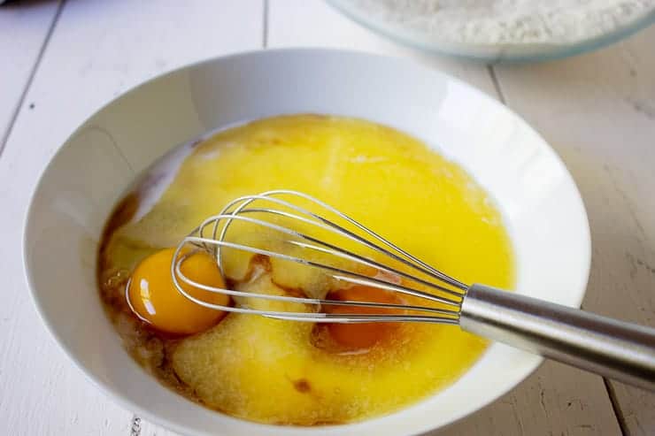 Eggs, butter, vanilla and milk being mixed in a white bowl.