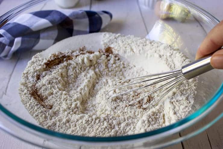 Flour, sugar and cinnamon being mixed together in a glass bowl.