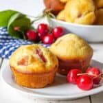 Two muffins filled with cherries on a white plate.