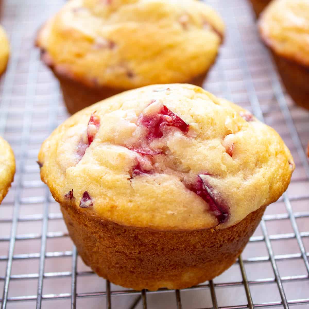 A muffin filled with cherries on a baking rack.