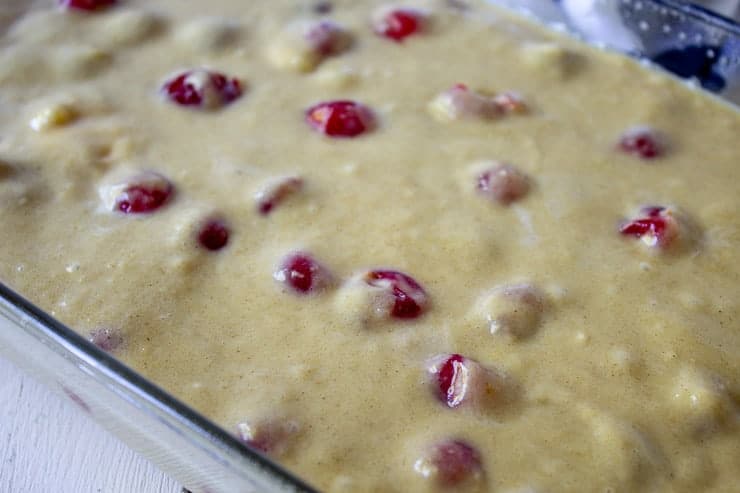Cake batter filled with fresh cherries in a baking dish.