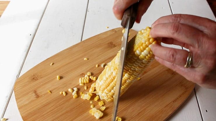 Cutting corn kernels off a cob.