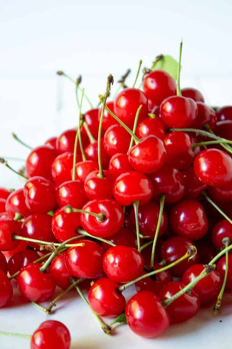 A pile of pie cherries on a white board.
