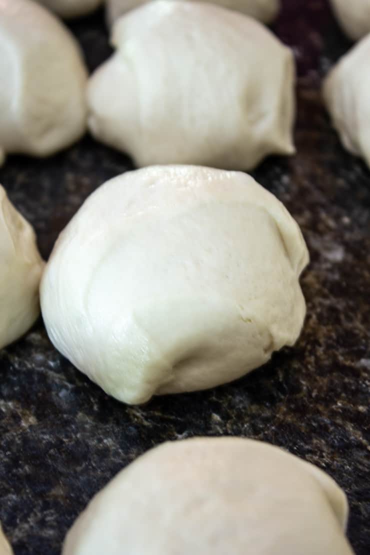 Round balls of bread dough sitting on a counter.