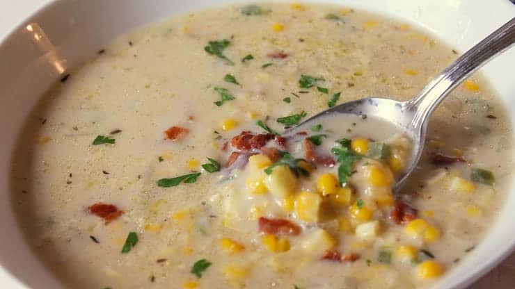 A bowlful of homemade soup with corn and bacon bits. 