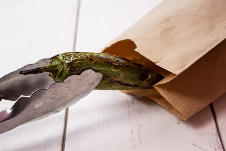 Roasted jalapeno pepper being placed into a paper bag.