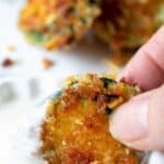 A fried zucchini chip being dipped into ranch dressing.