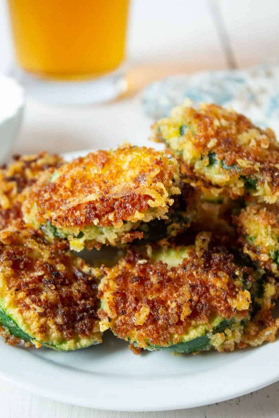 A white plate full of golden zucchini fries.